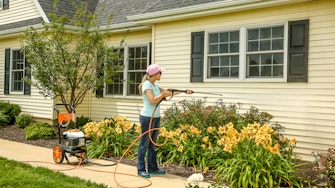 Woman cleaning siding with pressure washer