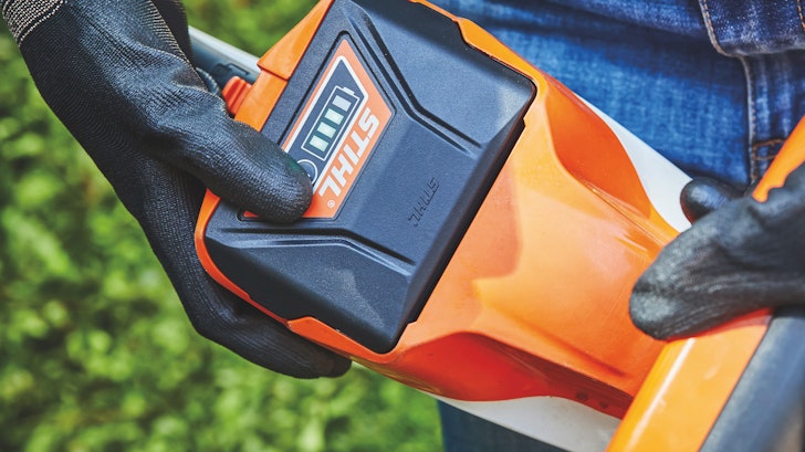 Man inserting battery into hedge trimmer