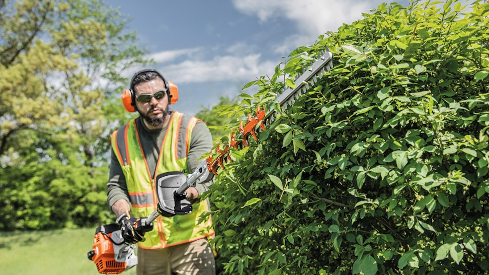 Man trimming hedges with extended reach hedge trimmer