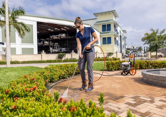 Woman using the RB 200 Pressure Washer on brick near a water fountain