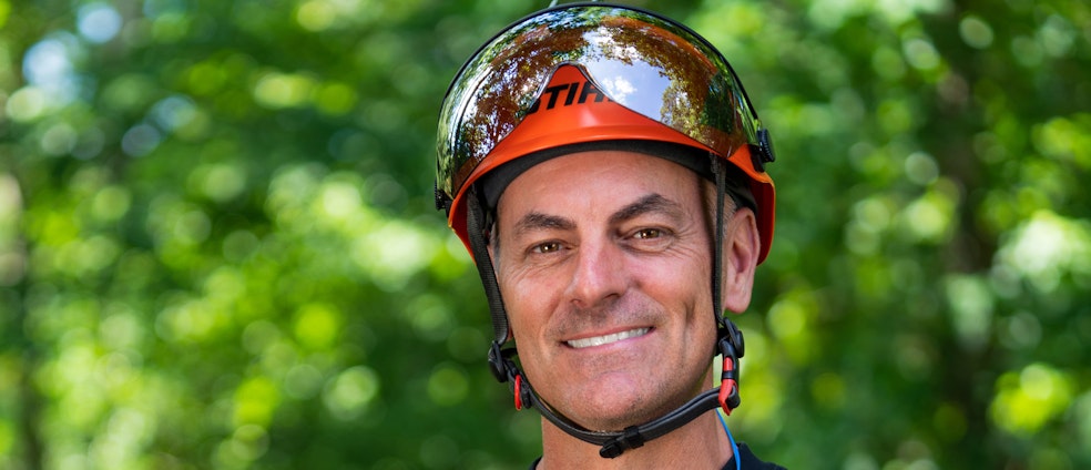 Portrait of Mark Chisholm, professional arborist, with green tree background