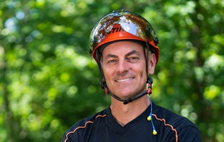 Portrait of Mark Chisholm, professional arborist, with green tree background