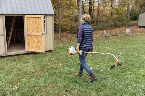 Woman putting STIHL trimmer in storage shed
