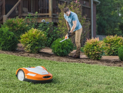 iMow mowing lawn while person in background trims bushes