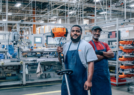 Two men inside the STIHL factory, smiling and looking proud. 