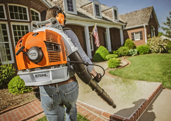 BR 600 Backpack Blower being used to blow grass off of a walk way.