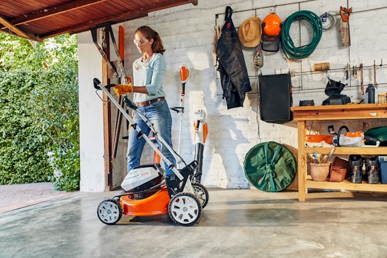 Woman folding the RMA 460 Mower to store in a garage.