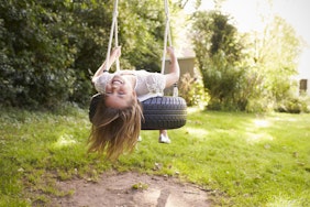 Girl smiling upside down on a tire swing