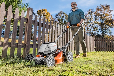 Man with RMA460 mowing grass near fence