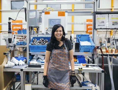 Woman leaning against assembly line at STIHL Factory