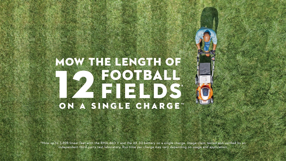 Man using the RMA 460 V mower with graphic element "Mow The Length of 12 Football Fields* On A Single Charge ™