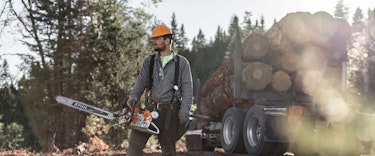 Professional logger wearing personal protective equipment and holding STIHL MS 661 C-M MAGNUM® chainsaw