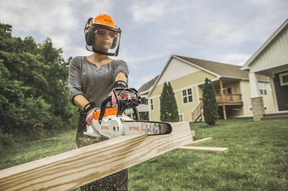 Woman using STIHL chainsaw in backyard of residential home
