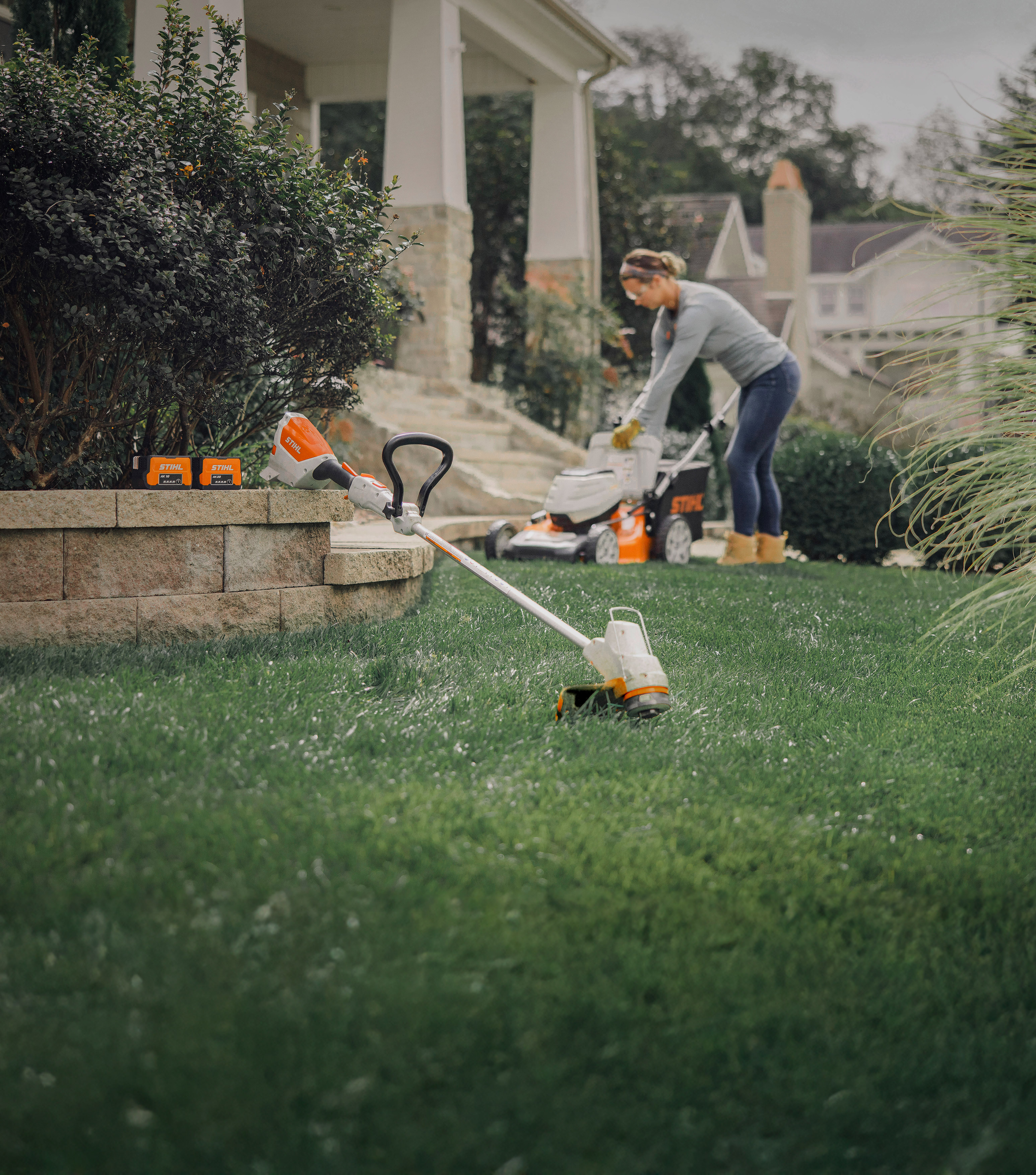 Women emptying RMA 460 in the background with battery trimmer and two batteries in the front.