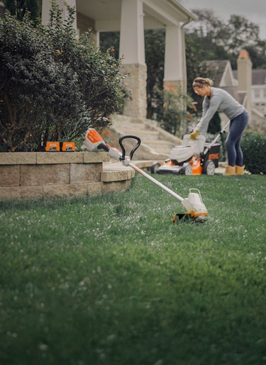 RMA 460 and FSA 57 with batteries Women emptying RMA 460 in the background with battery trimmer and two batteries in the front.