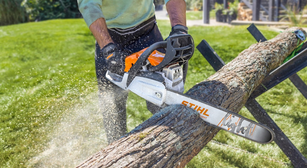 Person using STIHL chainsaw to cut wood