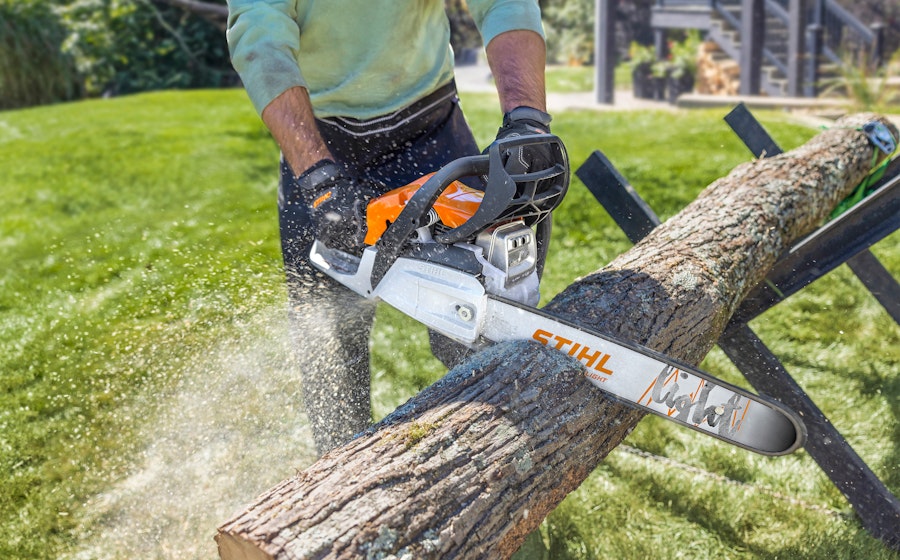 Person using STIHL chainsaw to cut wood