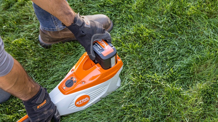 Person putting STIHL battery into trimmer tool